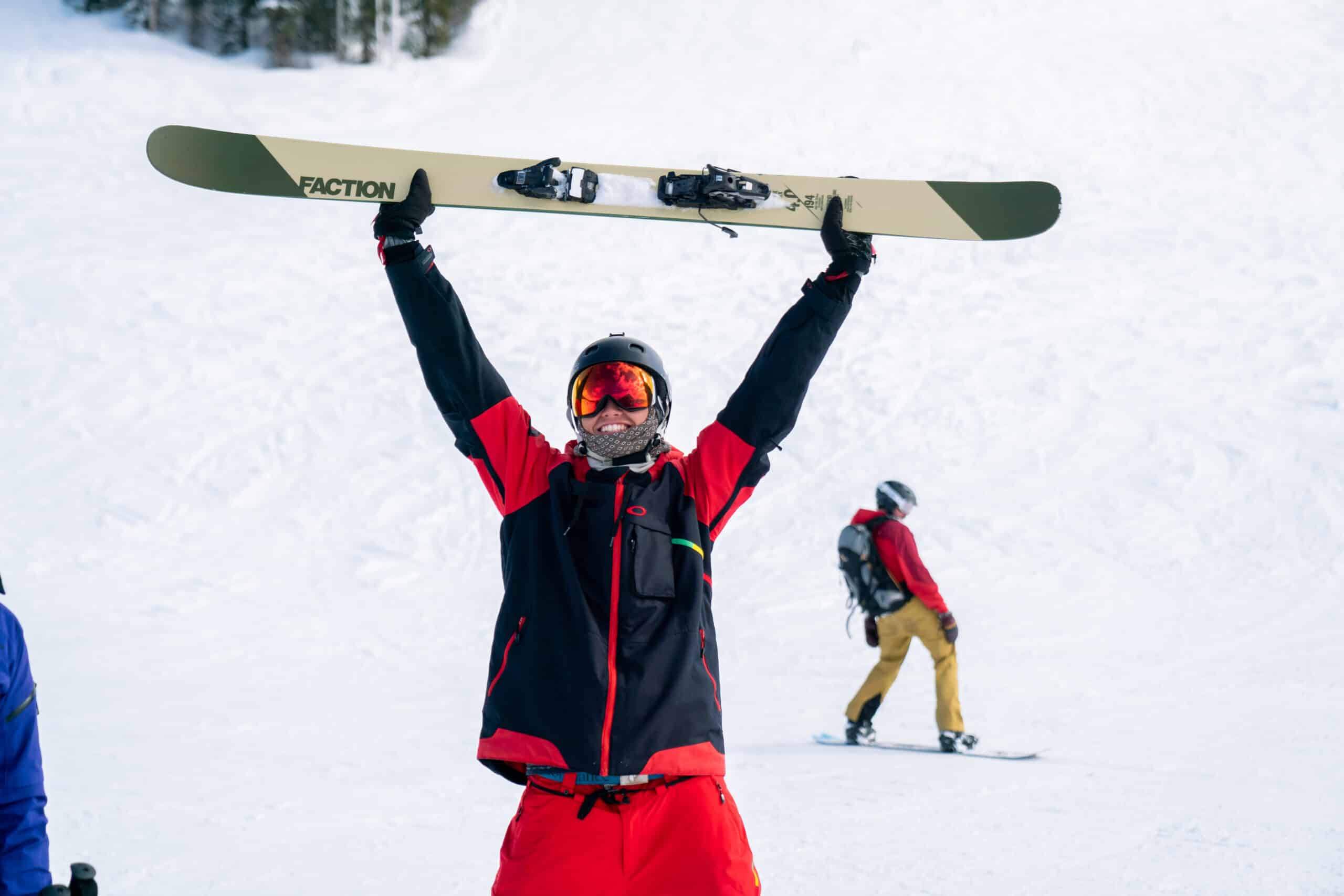 skier in red jacket raising skies